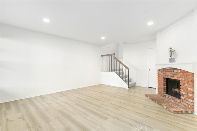 unfurnished living room featuring light hardwood / wood-style floors and a brick fireplace