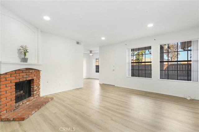 unfurnished living room featuring a brick fireplace, light hardwood / wood-style floors, and ceiling fan