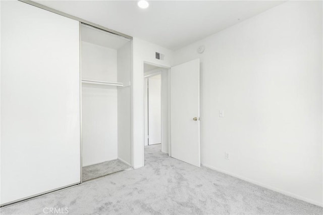 unfurnished bedroom with light colored carpet and a closet