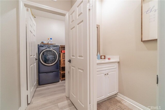 laundry area with washer / dryer and light hardwood / wood-style floors