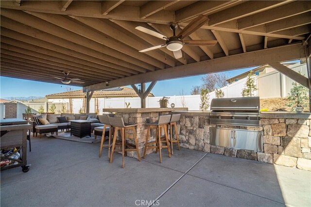 view of patio with area for grilling, ceiling fan, a bar, and an outdoor hangout area