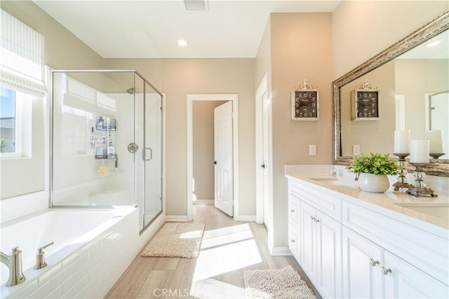 bathroom featuring hardwood / wood-style flooring, vanity, and separate shower and tub