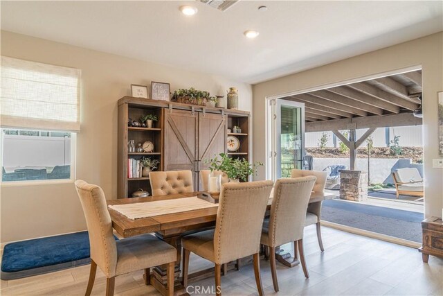 dining room with light wood-type flooring and a barn door