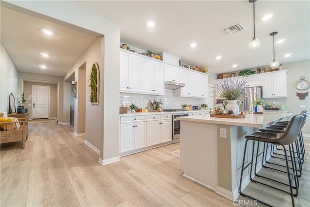 kitchen featuring decorative light fixtures, a kitchen breakfast bar, and white cabinets