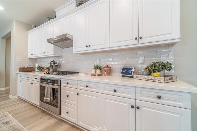 kitchen featuring tasteful backsplash, appliances with stainless steel finishes, white cabinetry, and light hardwood / wood-style floors