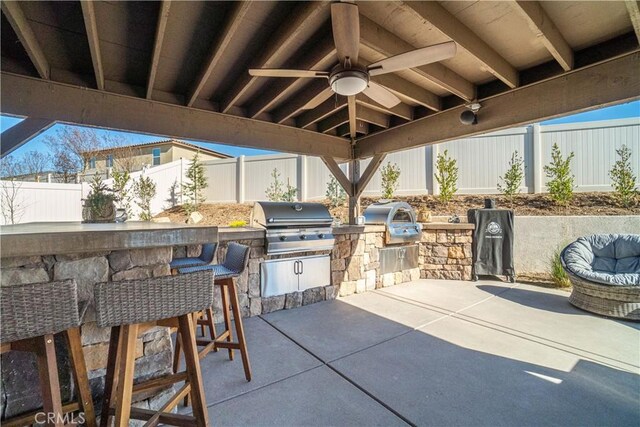 view of patio with exterior kitchen, a bar, grilling area, and ceiling fan