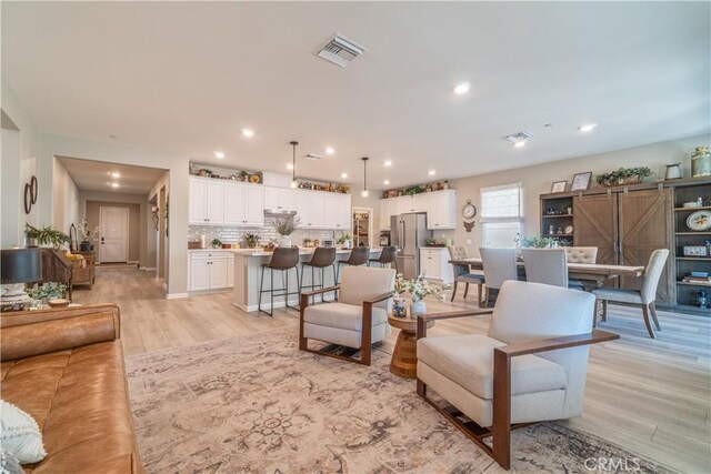 living room featuring a barn door and light hardwood / wood-style flooring