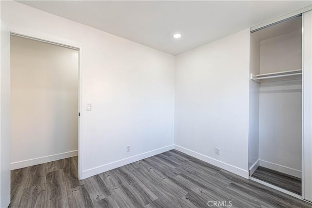 unfurnished bedroom with dark hardwood / wood-style floors and a closet