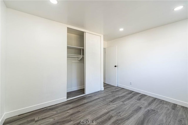 unfurnished bedroom with dark wood-type flooring and a closet