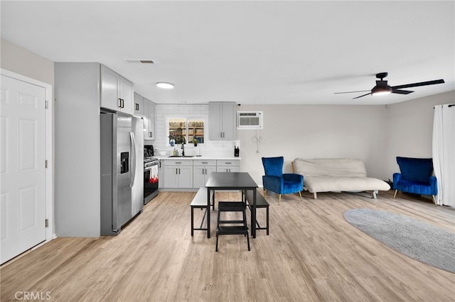 kitchen featuring ceiling fan, backsplash, sink, light hardwood / wood-style flooring, and stainless steel appliances