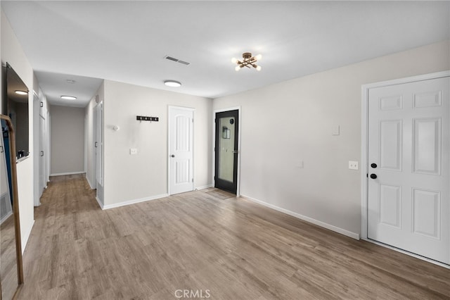 empty room featuring a chandelier and light hardwood / wood-style flooring