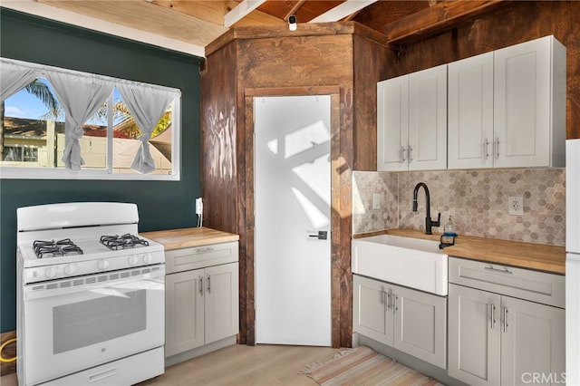 kitchen with gas range gas stove, decorative backsplash, butcher block countertops, sink, and white cabinetry