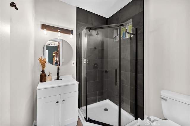 bathroom with toilet, an enclosed shower, and vanity