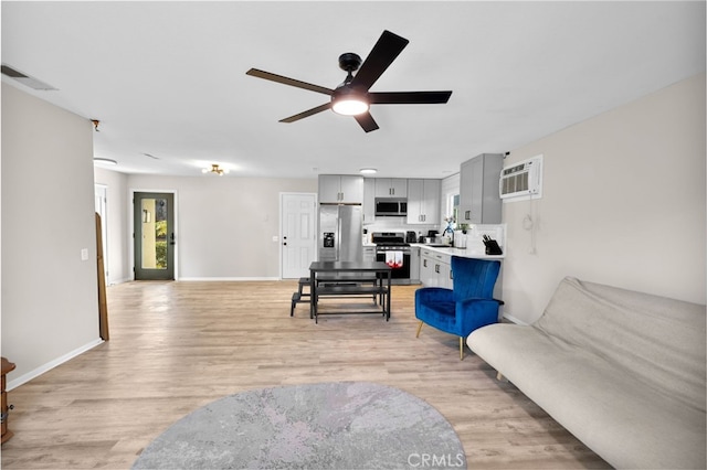 living room with light wood-type flooring, ceiling fan, and a wall unit AC