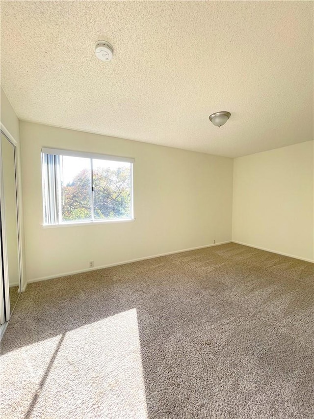 spare room featuring carpet floors and a textured ceiling