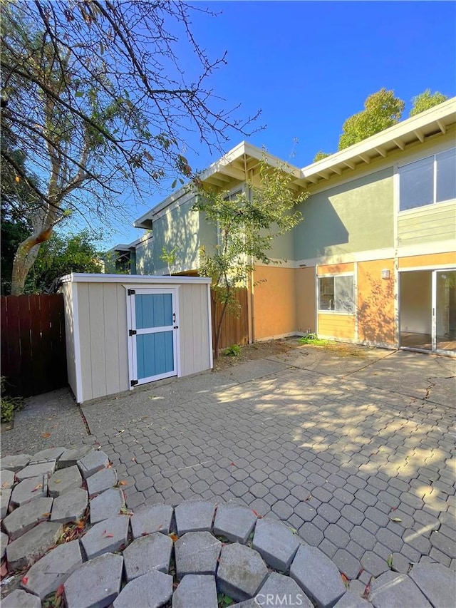 rear view of property featuring a storage unit and a patio