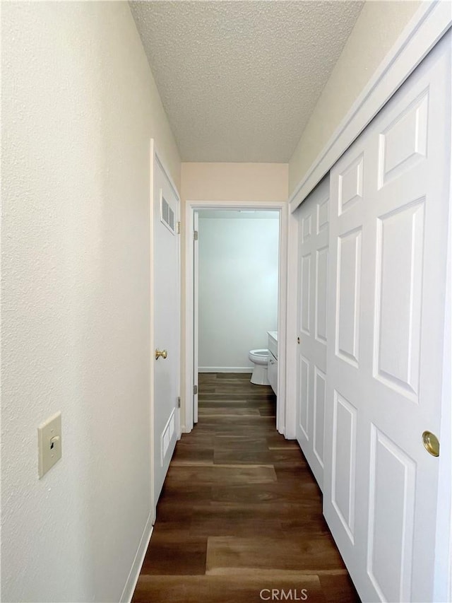 hall featuring a textured ceiling and dark hardwood / wood-style floors