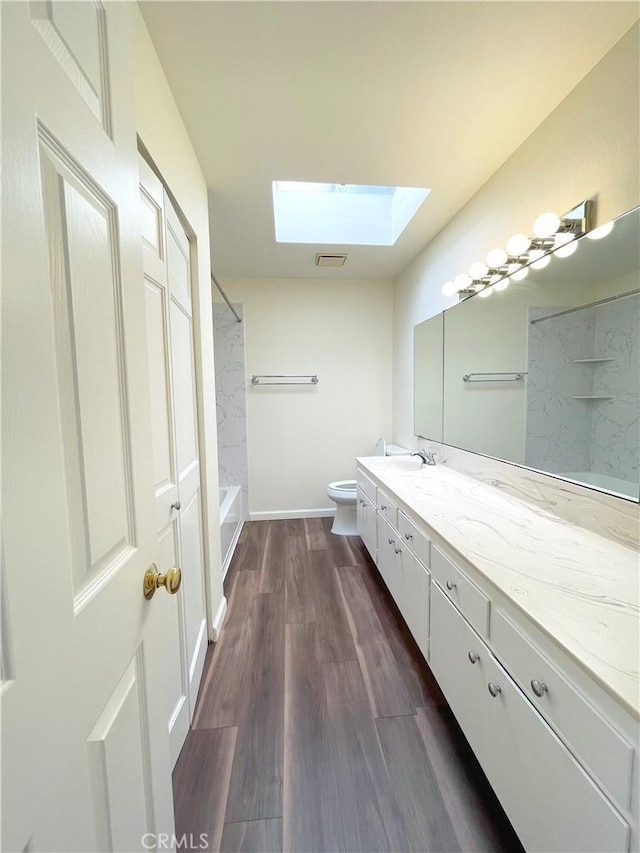 bathroom featuring toilet, a skylight, hardwood / wood-style floors, and vanity