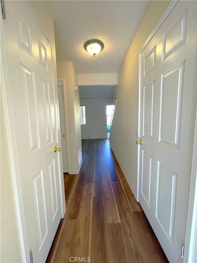 hallway with dark wood-type flooring and a textured ceiling