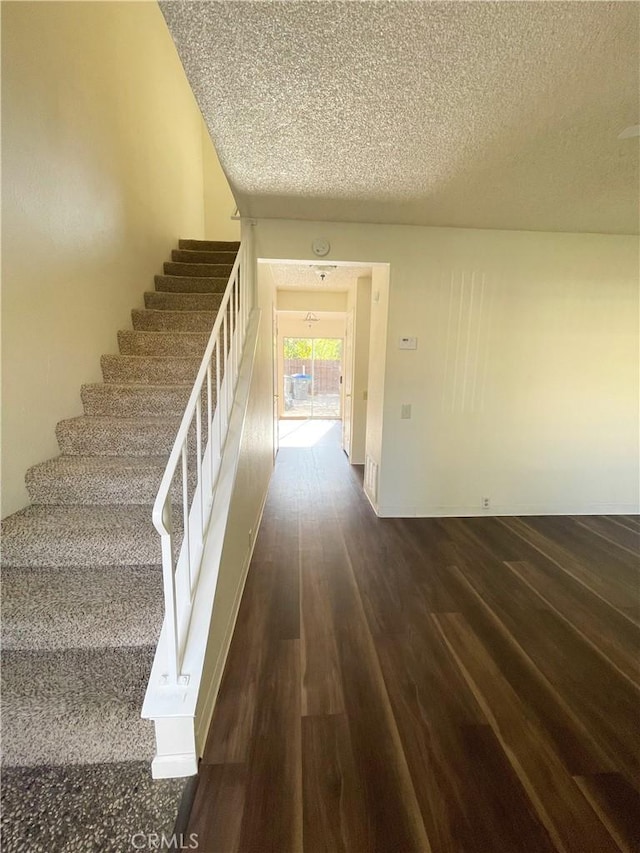 staircase with hardwood / wood-style flooring and a textured ceiling