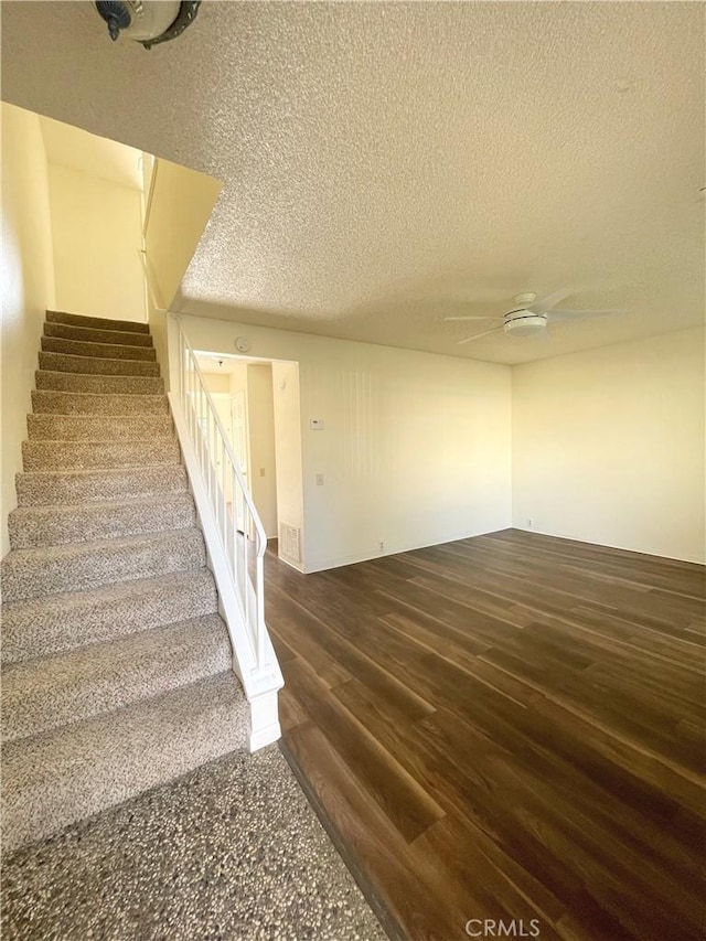 stairs featuring a textured ceiling, ceiling fan, and hardwood / wood-style floors