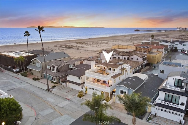 aerial view at dusk with a beach view and a water view