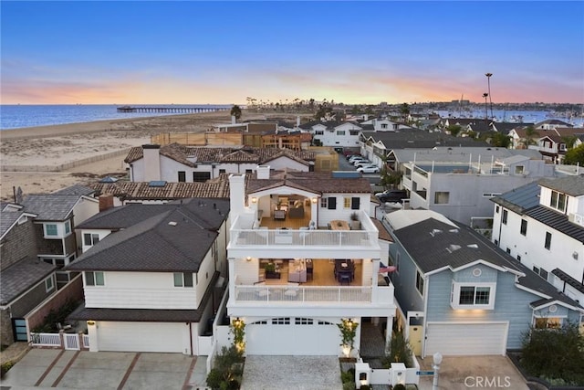 aerial view at dusk featuring a view of the beach and a water view