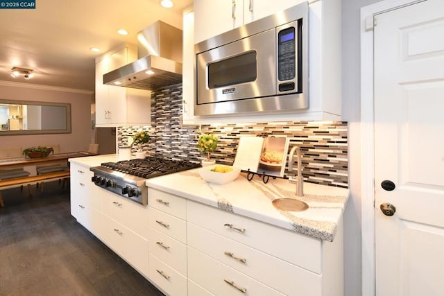 kitchen featuring appliances with stainless steel finishes, extractor fan, white cabinetry, and light stone counters