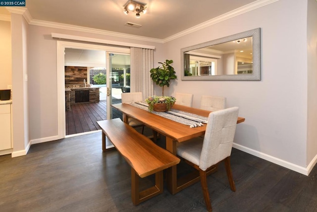 dining room featuring sink, dark hardwood / wood-style floors, and crown molding