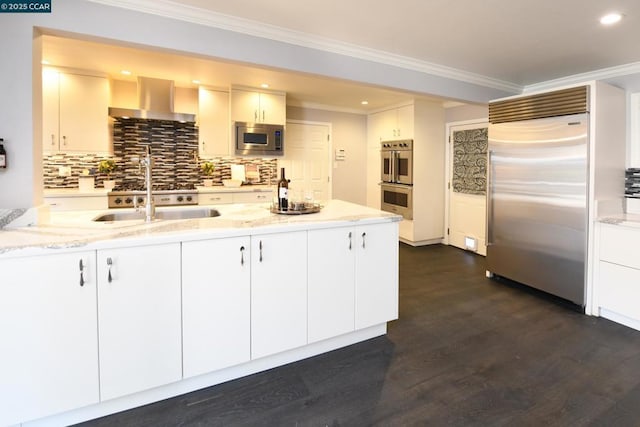 kitchen with exhaust hood, built in appliances, crown molding, white cabinets, and sink