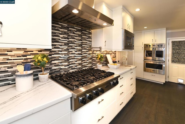 kitchen with backsplash, extractor fan, white cabinetry, light stone countertops, and appliances with stainless steel finishes