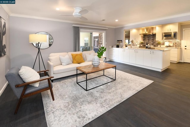 living room featuring ceiling fan, dark hardwood / wood-style floors, sink, and crown molding