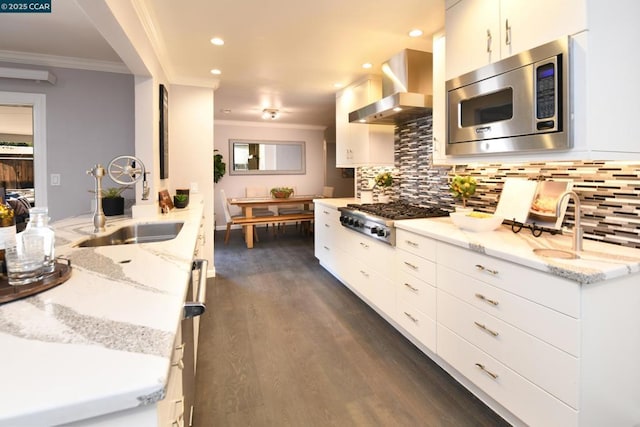 kitchen with light stone counters, sink, wall chimney exhaust hood, and appliances with stainless steel finishes