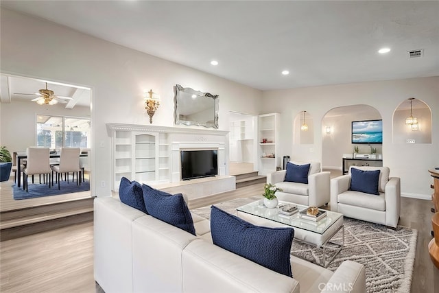 living room with light hardwood / wood-style floors, beam ceiling, and ceiling fan