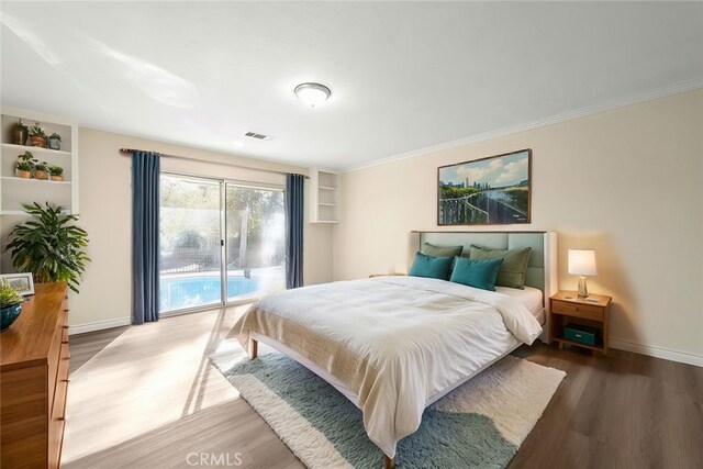 bedroom featuring dark wood-type flooring, crown molding, and access to outside