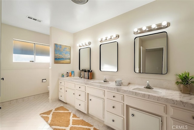 bathroom with toilet, vanity, and tile patterned flooring