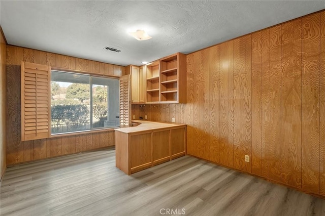 unfurnished office featuring a textured ceiling, light hardwood / wood-style flooring, and wood walls