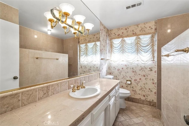 bathroom with toilet, tile patterned floors, vanity, and a notable chandelier