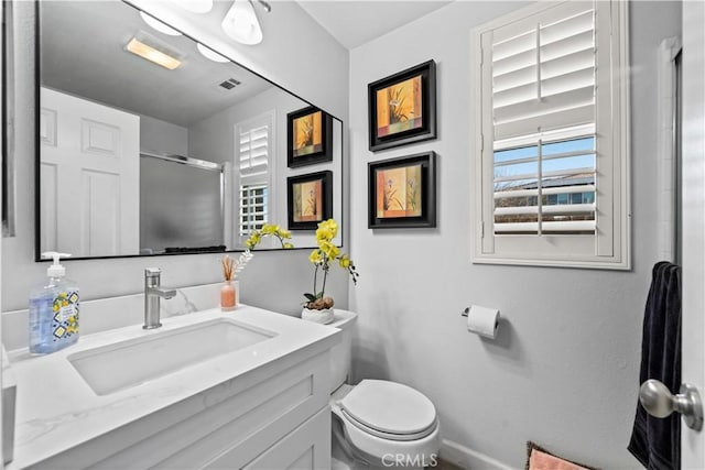 bathroom featuring vanity, toilet, and a shower with door