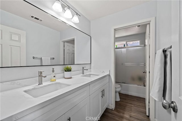 full bathroom with toilet, vanity, shower / bath combination with glass door, and hardwood / wood-style floors