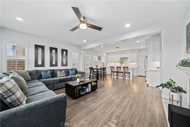 living room with light hardwood / wood-style floors and ceiling fan