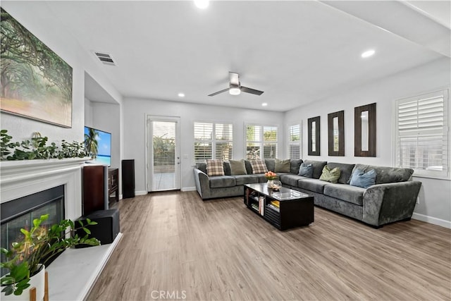 living room with ceiling fan, plenty of natural light, and light wood-type flooring