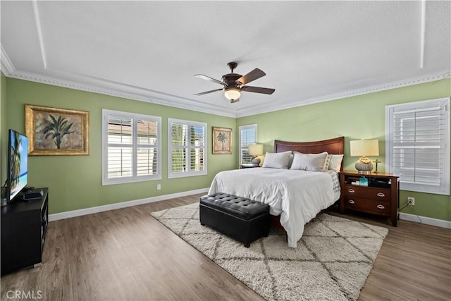 bedroom featuring wood-type flooring, crown molding, and ceiling fan