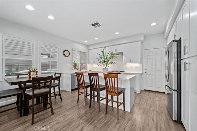 kitchen featuring light hardwood / wood-style flooring, a breakfast bar, stainless steel appliances, a center island, and white cabinets