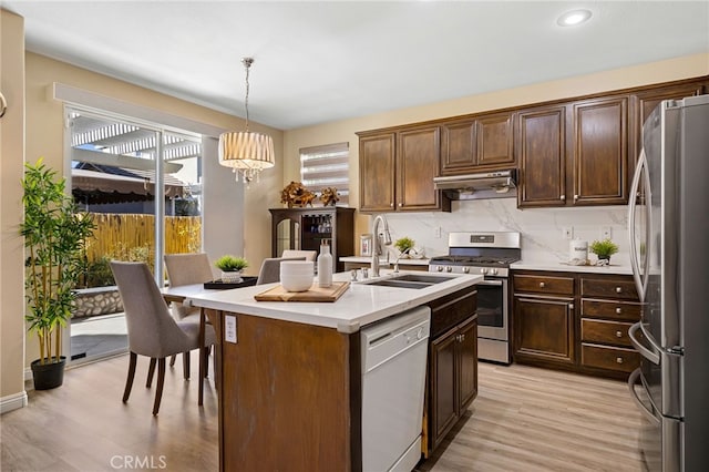 kitchen with stainless steel appliances, sink, hanging light fixtures, a kitchen island with sink, and a notable chandelier