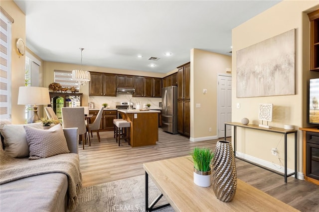 living room with a chandelier, light hardwood / wood-style floors, and sink