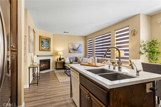 kitchen featuring light wood-type flooring, dishwasher, stainless steel refrigerator, dark brown cabinetry, and sink