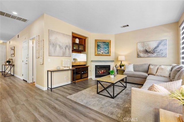 living room with a high end fireplace and light hardwood / wood-style floors