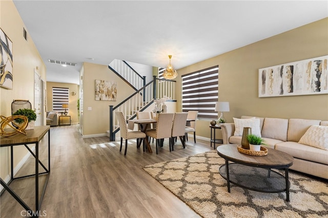 living room featuring plenty of natural light, wood-type flooring, and an inviting chandelier