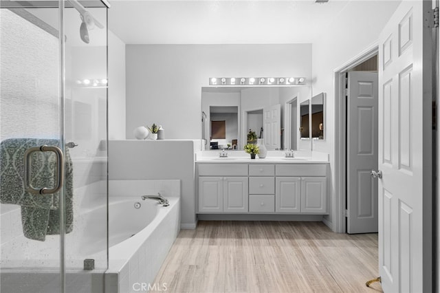 bathroom with hardwood / wood-style flooring, vanity, and plus walk in shower